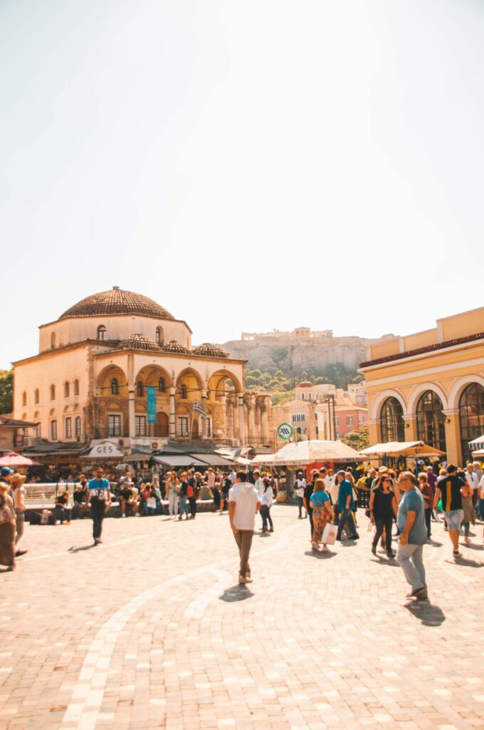 Lively scene at Monastiraki Square in Athens with people enjoying a sunny day, historic architecture in view.