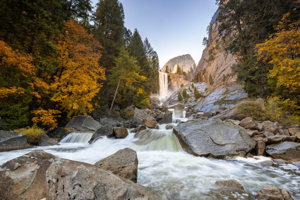 Yosemite Falls with vibrant autumn colors and flowing river in Yosemite National Park, California.